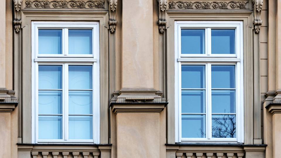 Janelas de madeira clássicas em fachada histórica com acabamento branco