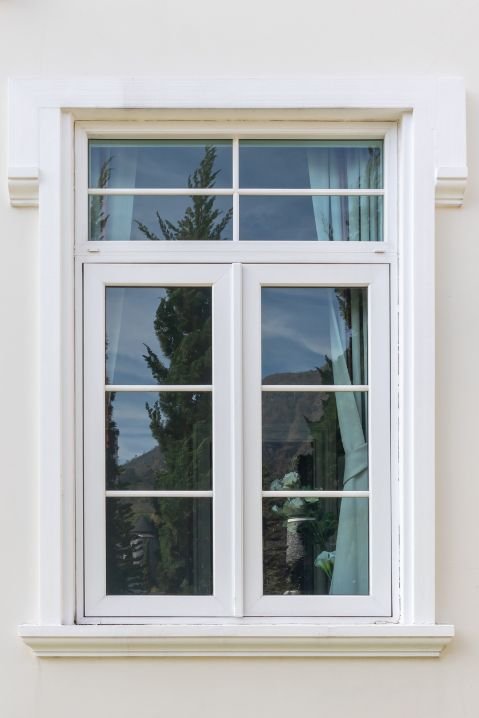 Janelas de madeira redondas com acabamento branco em fachada residencial clássica