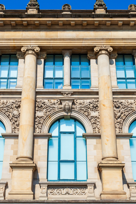 Janelas de madeira em edifício monumental com colunas e detalhes arquitetônicos